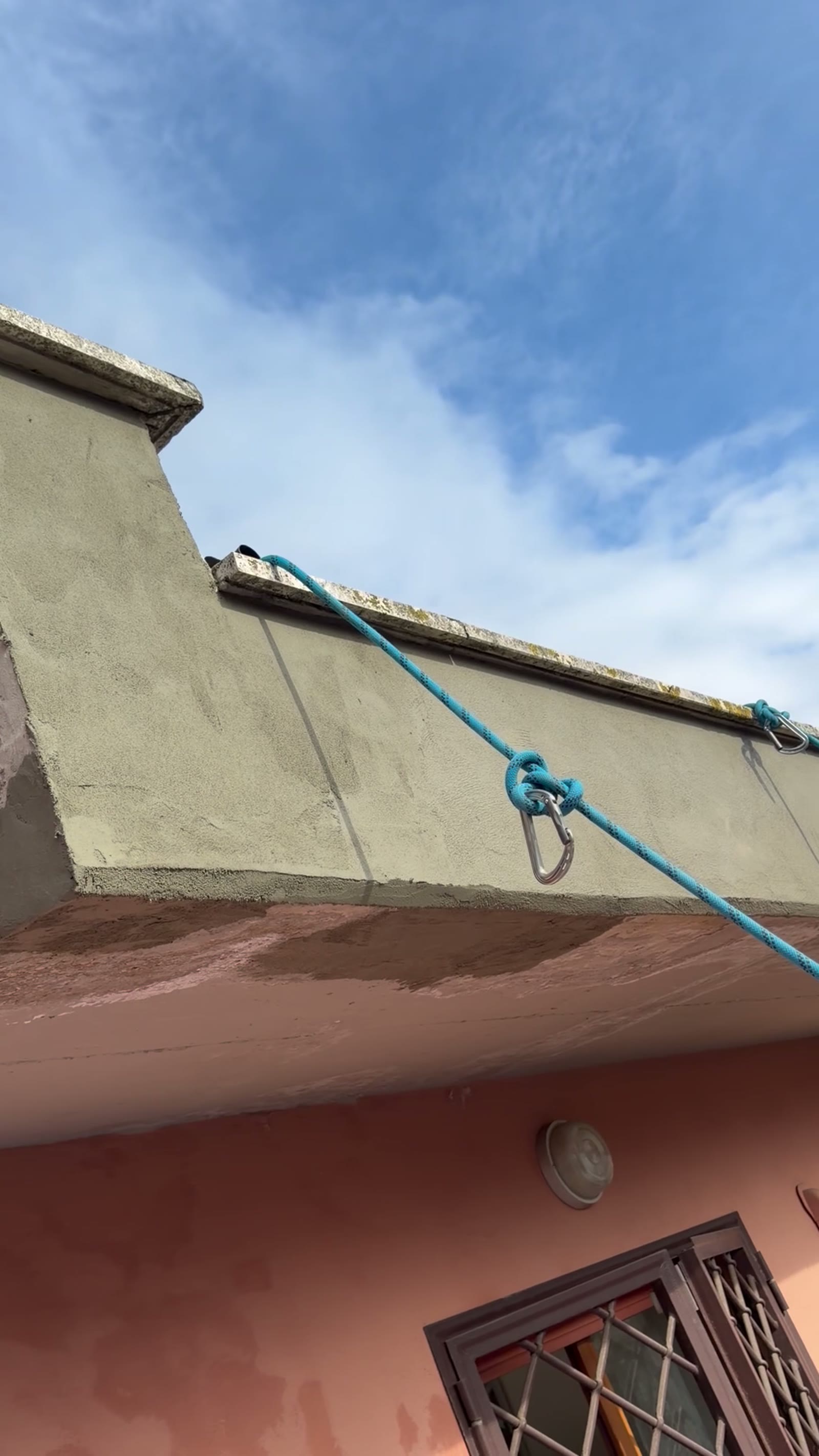 Ancoraggio con corda blu e moschettone su parapetto di copertura