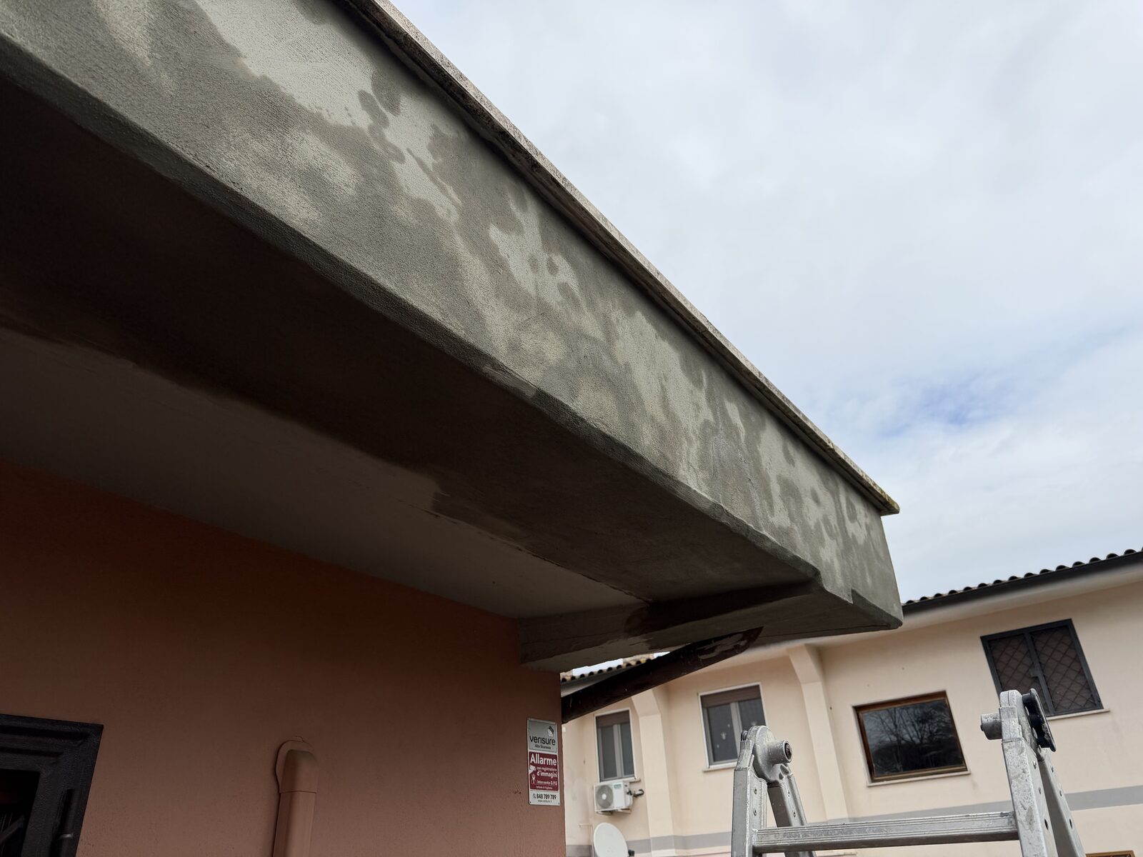 Cornicione di villa con macchie d'umidità e pellicola disgregata vista dal basso