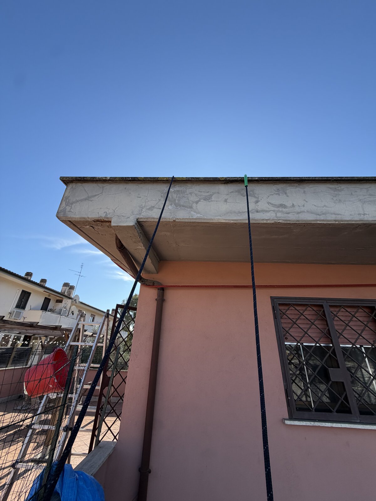 Spigolo di villa rosa con cornicione finito e corde di lavoro ancora calate